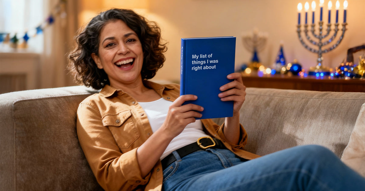 A woman laughing at her funny Hanukkah gift – a notebook entitled