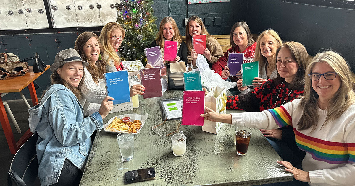 A team at a company party showing off their corporate gifting WTF Notebooks